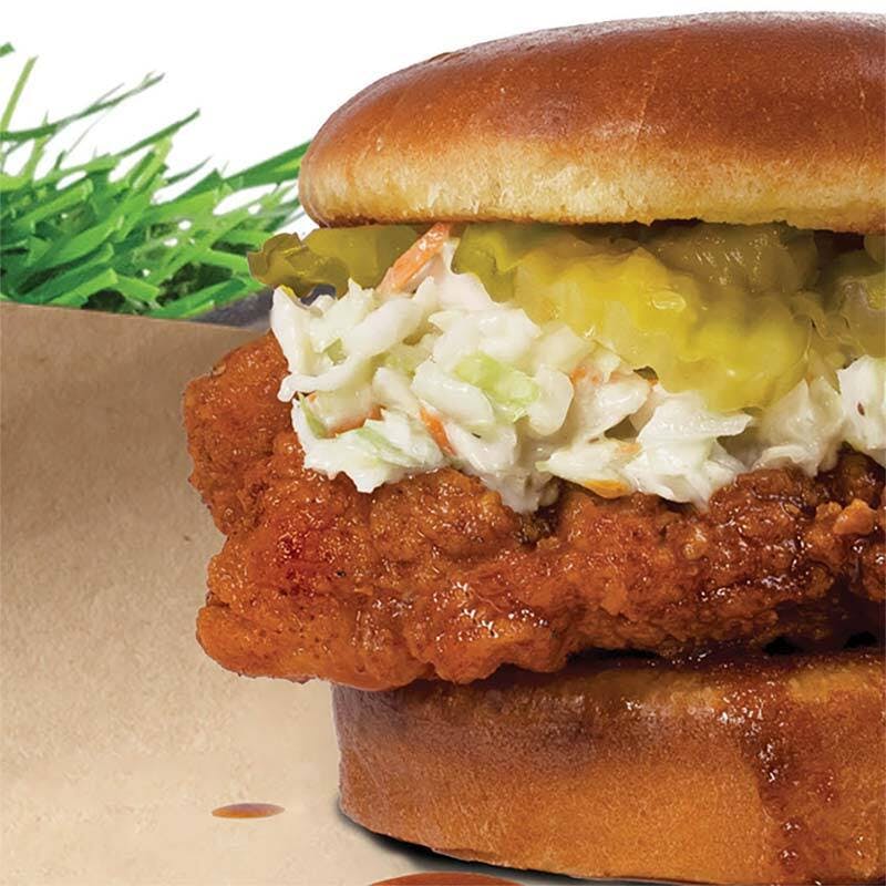 close up of hot chicken sandwich with coleslaw pickles on a brioche bun
